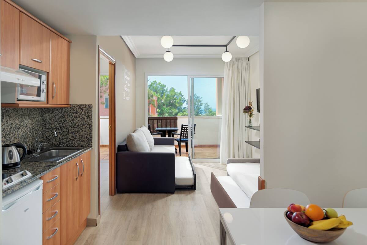 A modern kitchen with granite countertops, a built-in oven, and a dining area with a sofa and table.