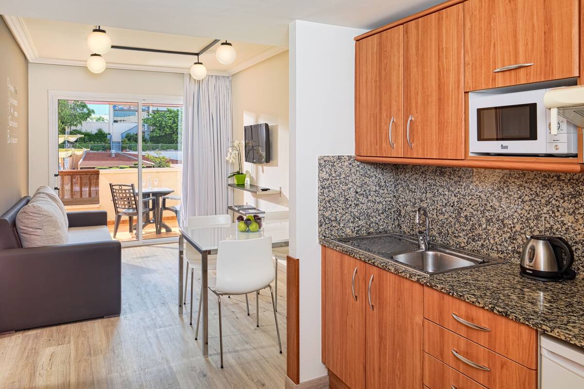 A modern kitchen with granite countertops, wooden cabinets, and a built-in microwave.