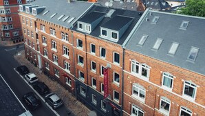Un immeuble de plusieurs étages, construit en briques, avec une rangée de fenêtres au rez-de-chaussée, qui semble être un hôtel ou un immeuble de bureaux.