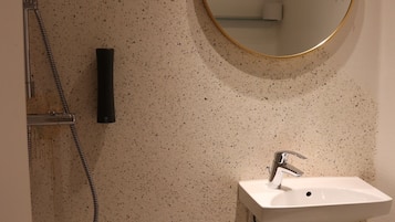 A bathroom with a white sink, a round mirror, and a shower.