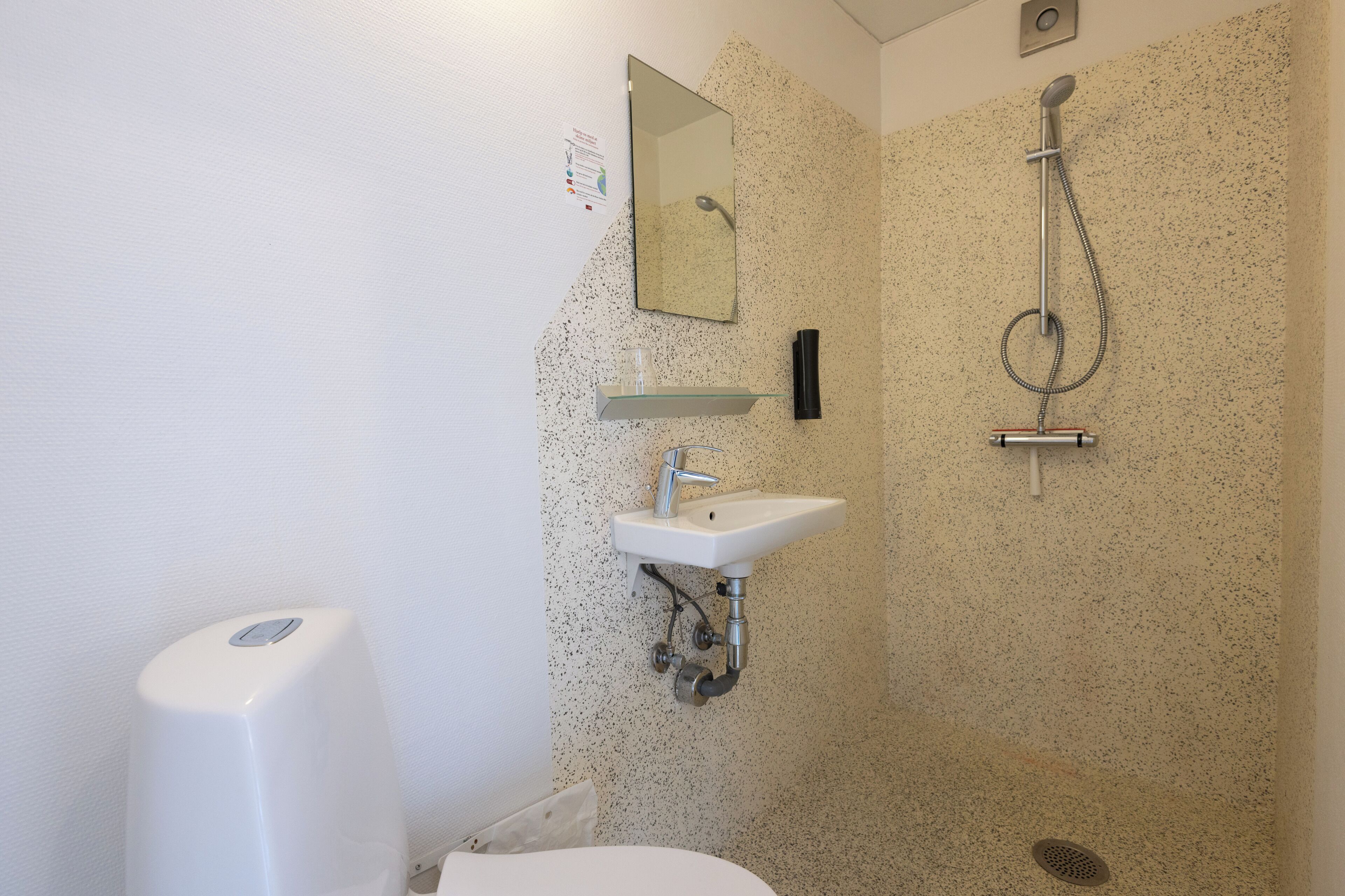 Une salle de bain avec un lavabo blanc, un miroir et une douche.