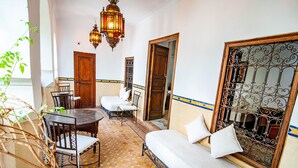 A room with a bed, a table with chairs, a potted plant, and a decorative iron gate.