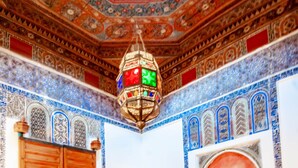 A room with a red sofa, wooden furniture, and intricate blue and red patterned walls and ceiling.