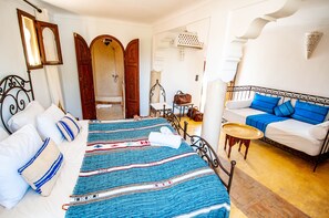 Quarto de hotel com cama, sofá, uma mesinha e guarda-roupa.
