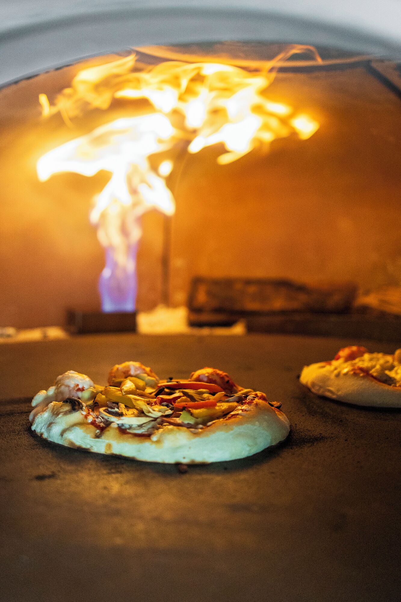 Un horno de pizza con pizzas cocinándose.