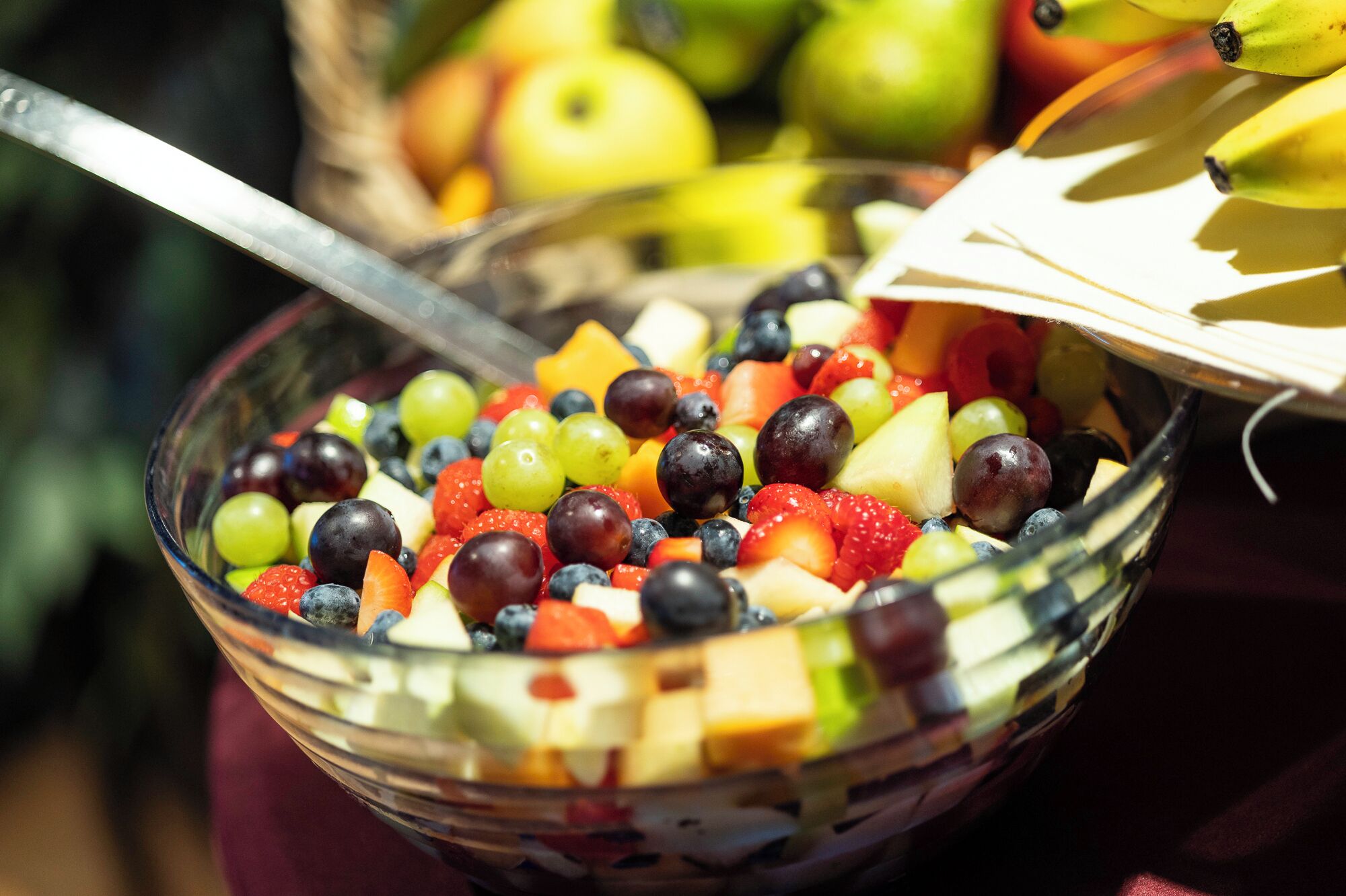 A bowl of mixed fruit salad with a spoon.