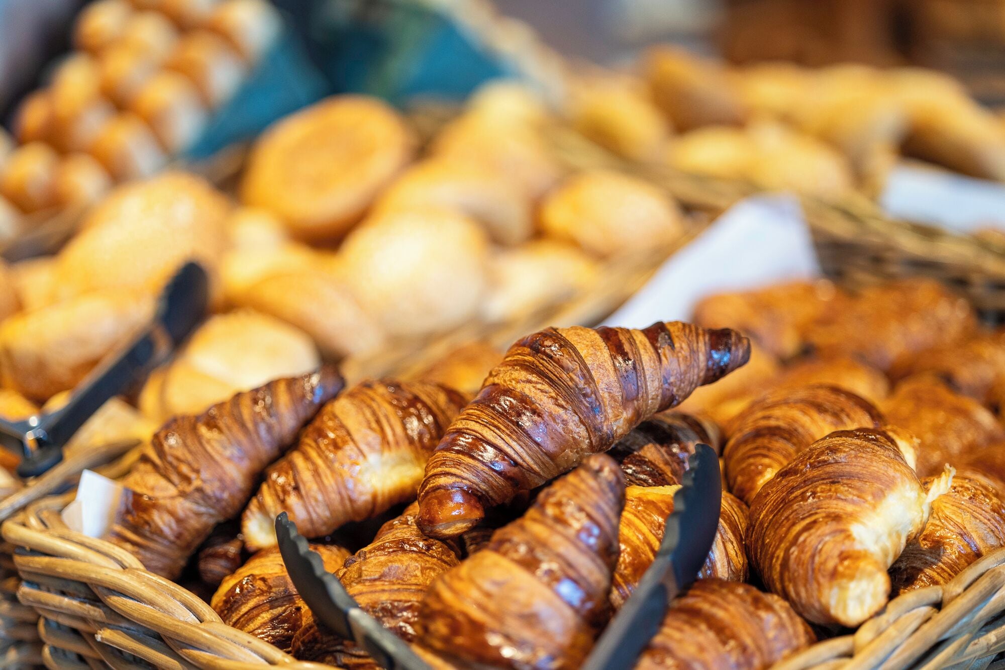 Una cesta llena de cruasanes y otros productos de panadería.