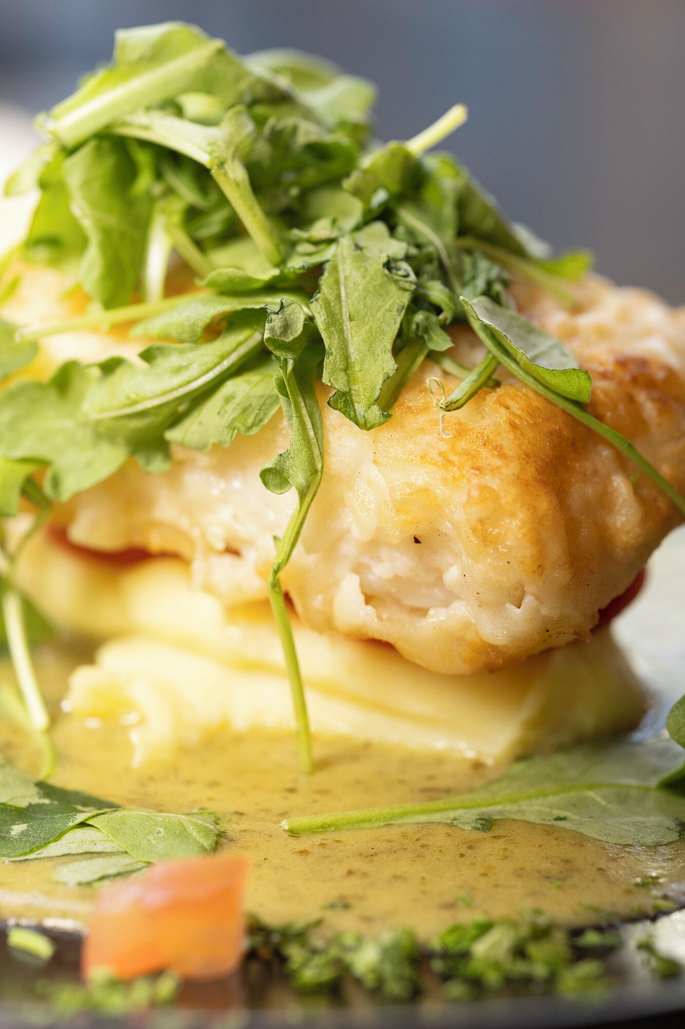 Un plat doté d’une croûte dorée et croustillante, d’une sauce crémeuse et de feuilles vertes fraîches.