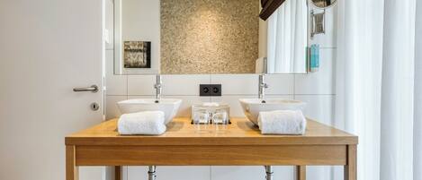 A bathroom with two sinks, a mirror, and a towel rack.