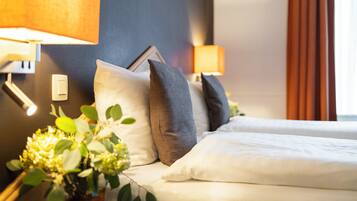 Ein Hotelzimmer mit zwei Betten, einem Nachttisch mit Lampe und einer Wandleuchte.