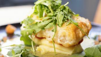 A close-up of a dish with a biscuit, cheese, and greens, possibly a salad or appetizer.