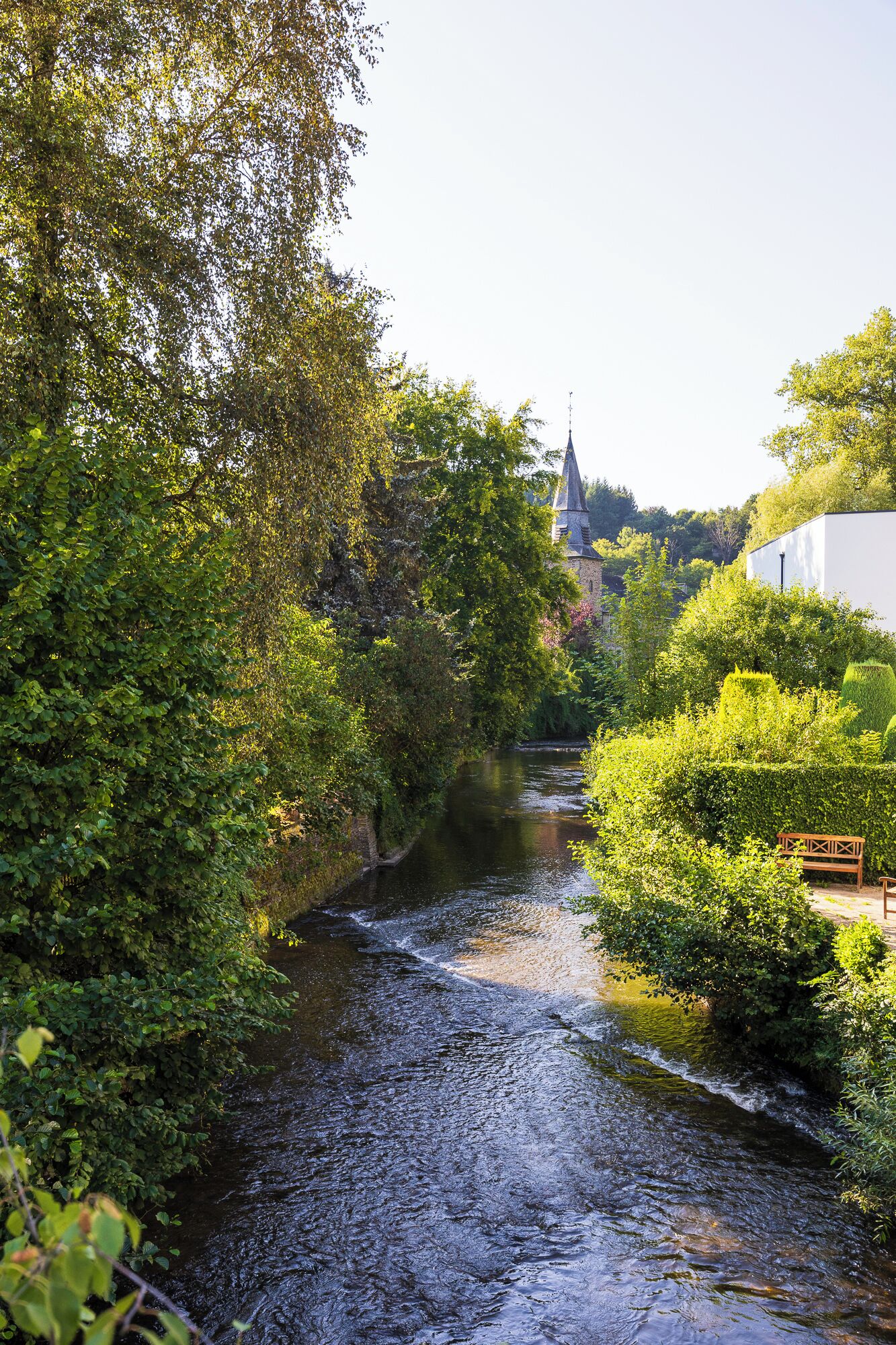 Een rivier die door een weelderig, groen landschap stroomt, met een kerk op de achtergrond.