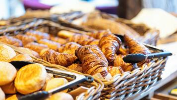 Un cesto pieno di dolci assortiti, tra cui croissant e panini.