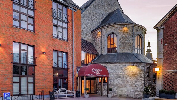 A historic building with a prominent tower and a red-brick facade. - Hotel Quartier Latin (Marche-en-Famenne)