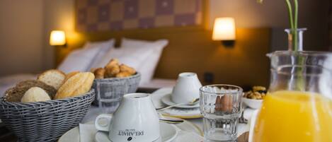 Ein Frühstücksbuffet mit Brot, Croissants, einer Tasse Kaffee, einem Glas Wasser und einem Glas Orangensaft.
