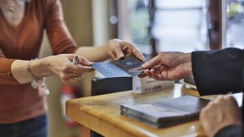 Une personne qui tend une carte de crédit à une autre personne au comptoir.