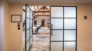 A hotel corridor with a glass door leading to a dining area.