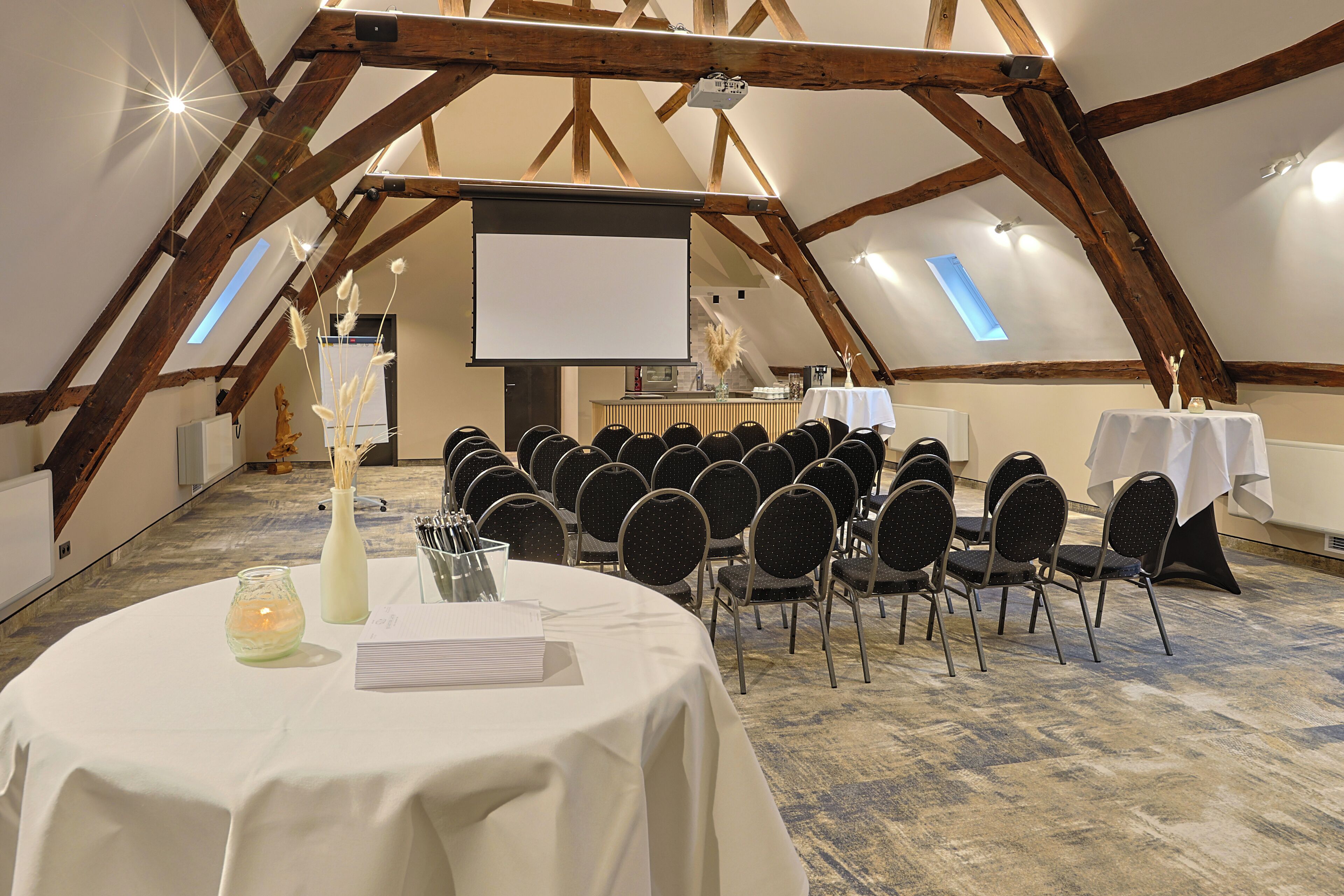 A conference room with a white table, chairs, and a projector screen.