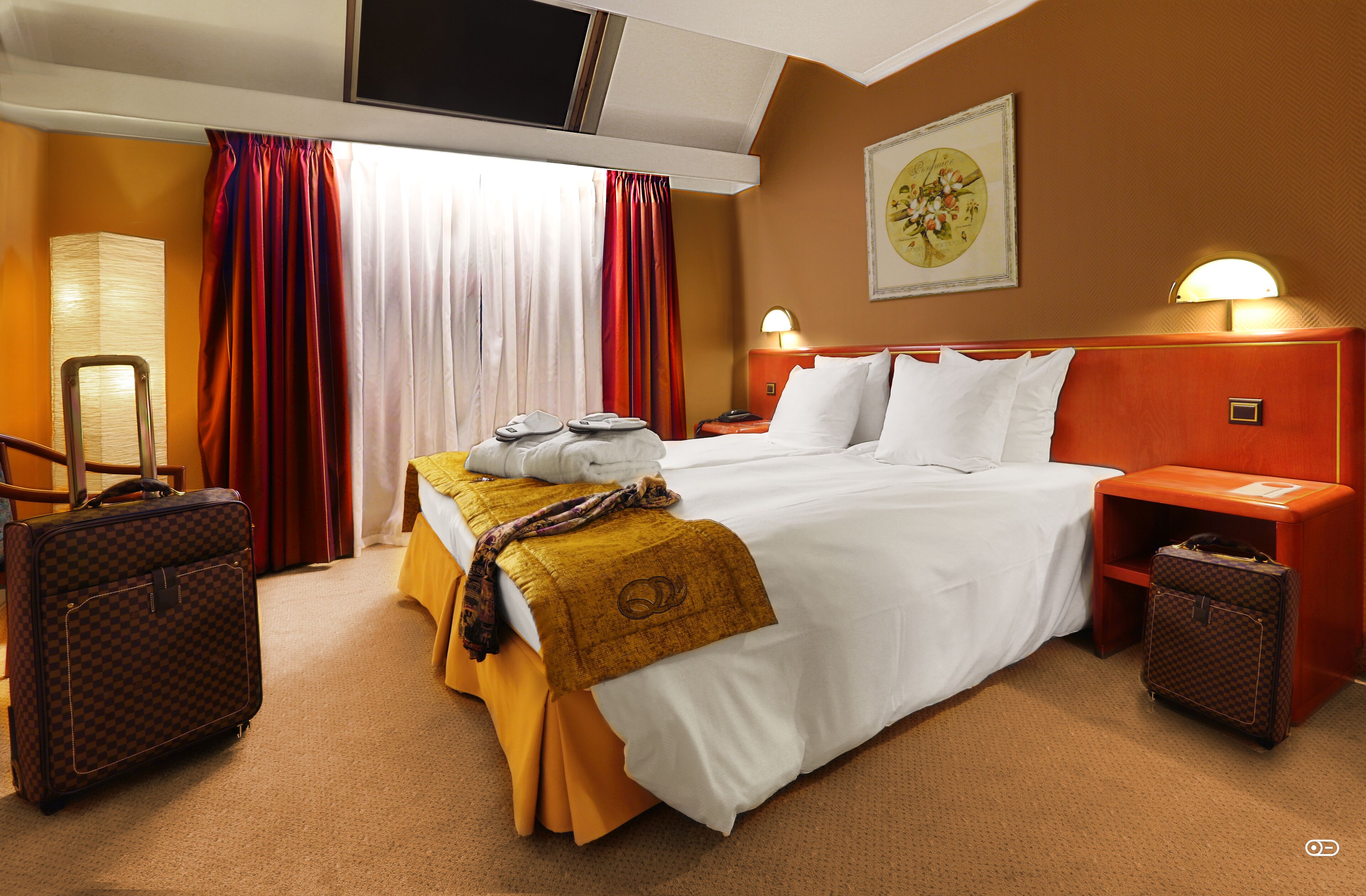 Une chambre d’hôtel avec un grand lit, deux tables de chevet, un bureau, une chaise, une lampe de bureau, un téléviseur et une fenêtre avec des rideaux.
