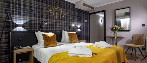 A hotel room with a large bed, a bedside table, a chair, and a small table with a vase of flowers.