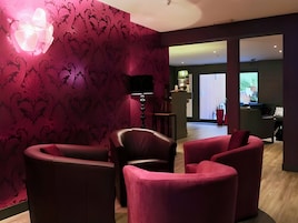 Una sala de estar moderna con papel tapiz estampado en rojo oscuro, sofás de cuero y un televisor de pantalla plana montado en la pared.