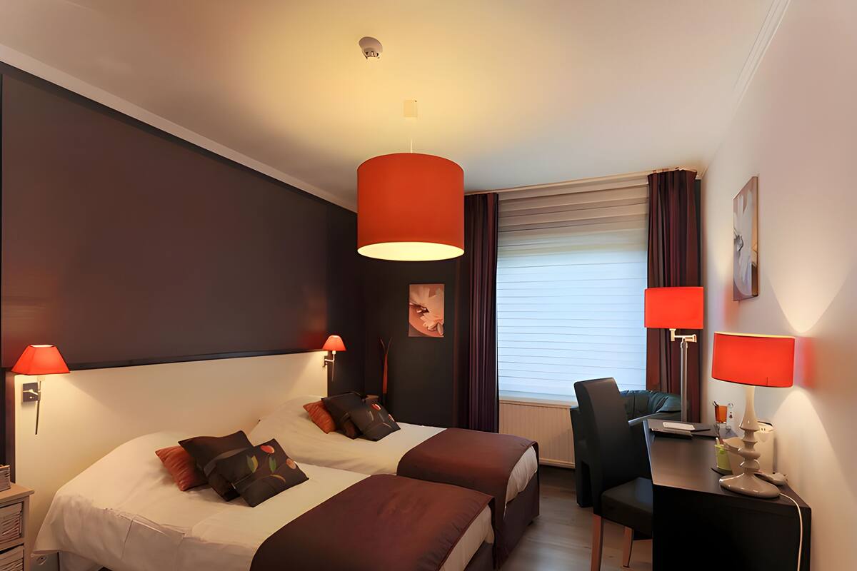 A hotel room with two beds, a desk, and a chair.