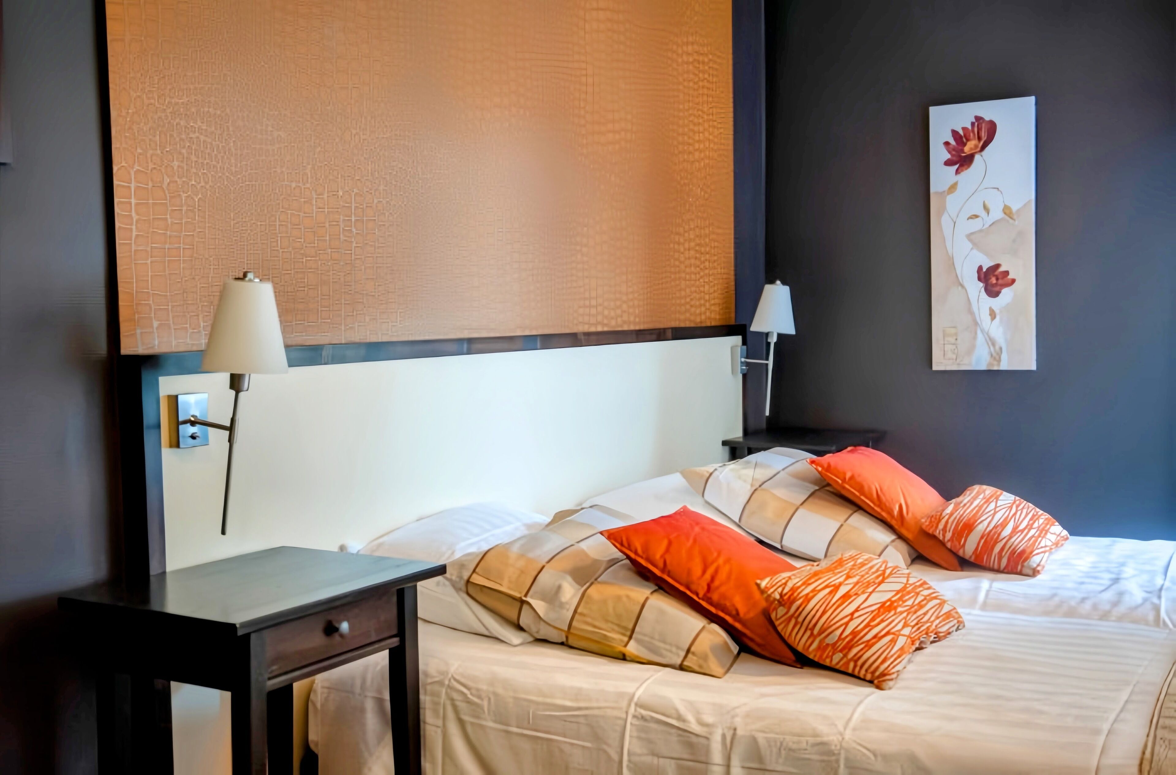 Una camera d'albergo con un letto, un comodino, una lampada e un quadro appeso al muro.