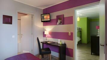 A bedroom with a bed, desk, chair, and a TV mounted on the wall.