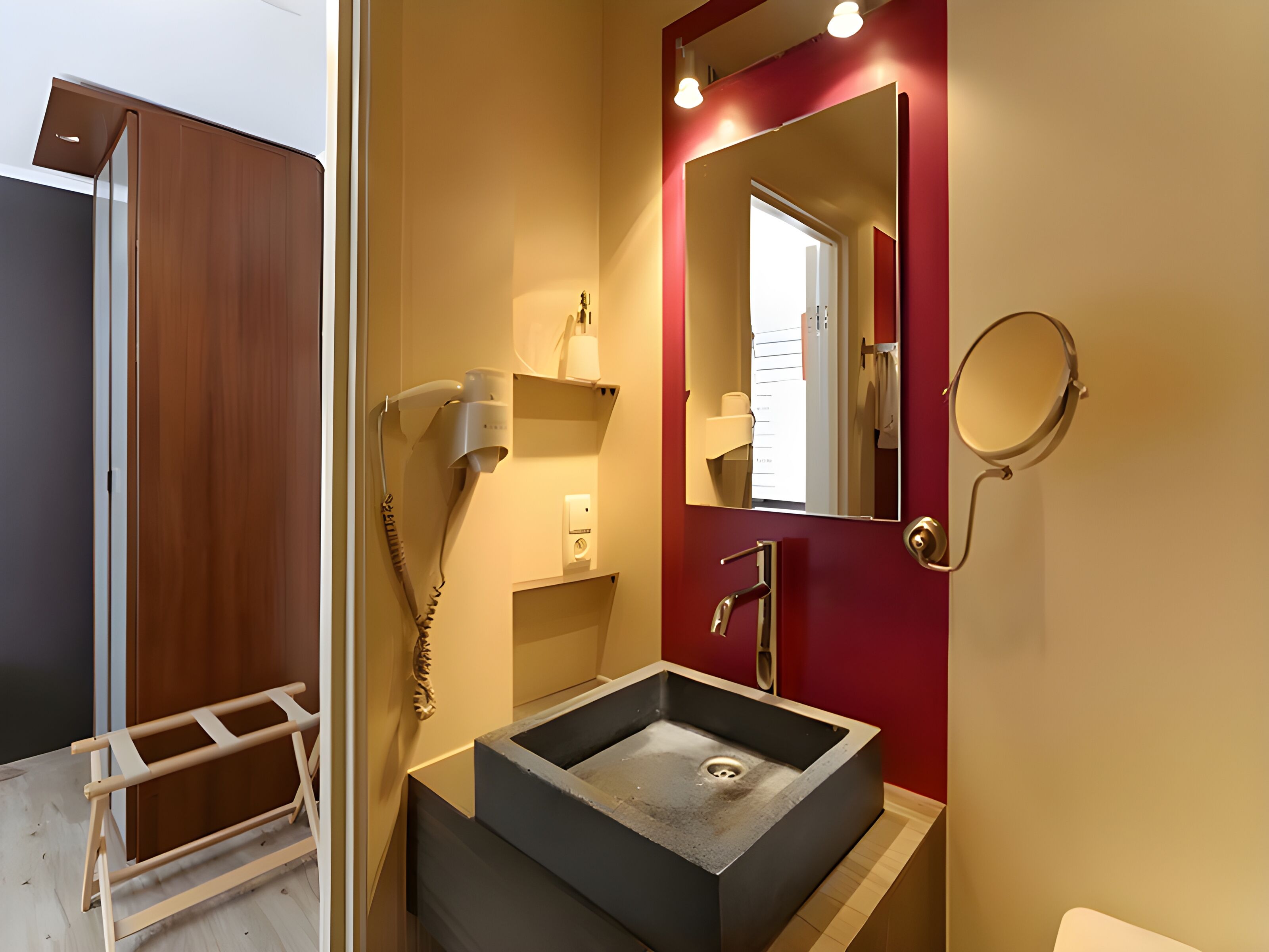 A modern bathroom with a large rectangular sink, a mirror, and a hairdryer mounted on the wall.