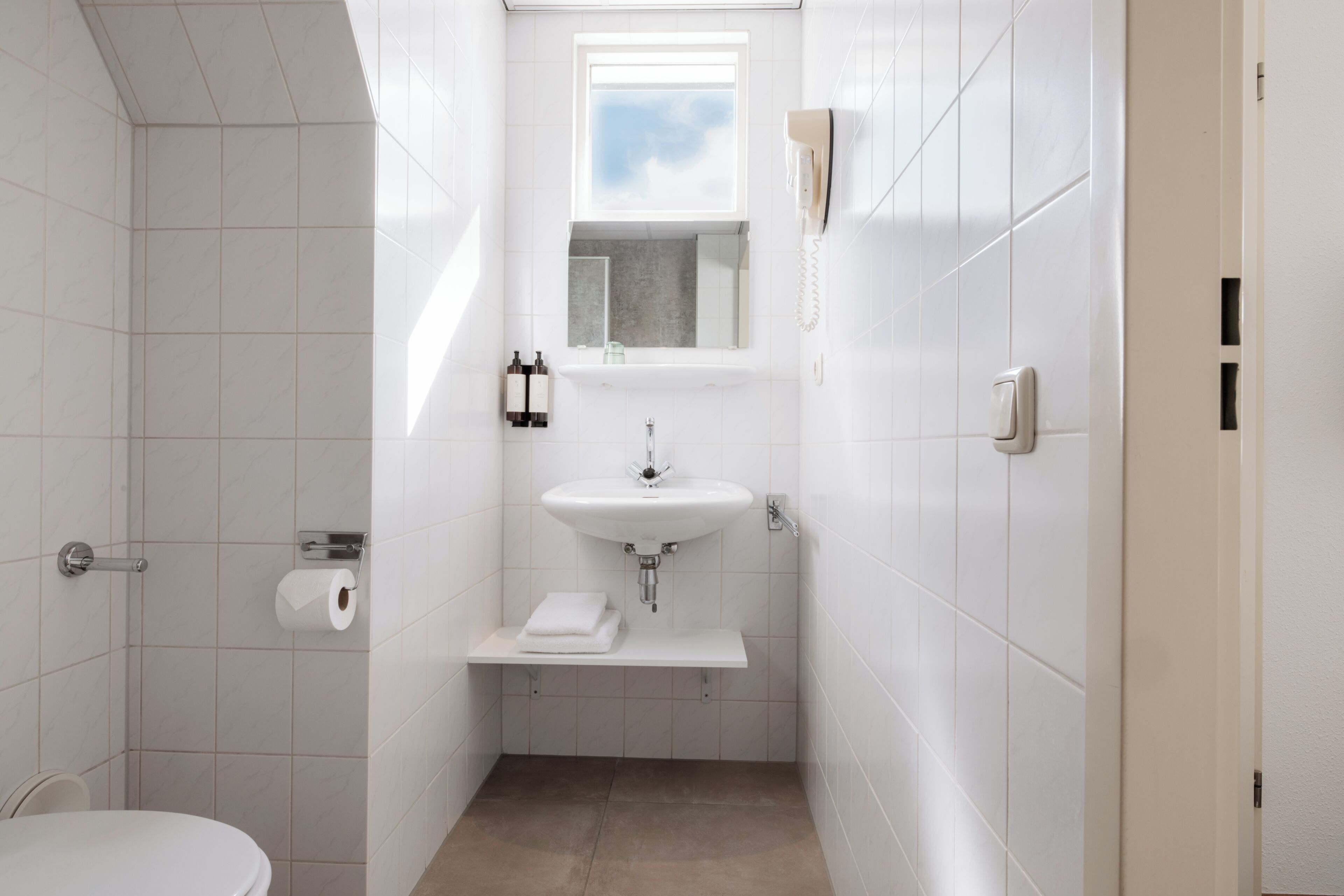A small, modern bathroom with a toilet, sink, and towel rack.