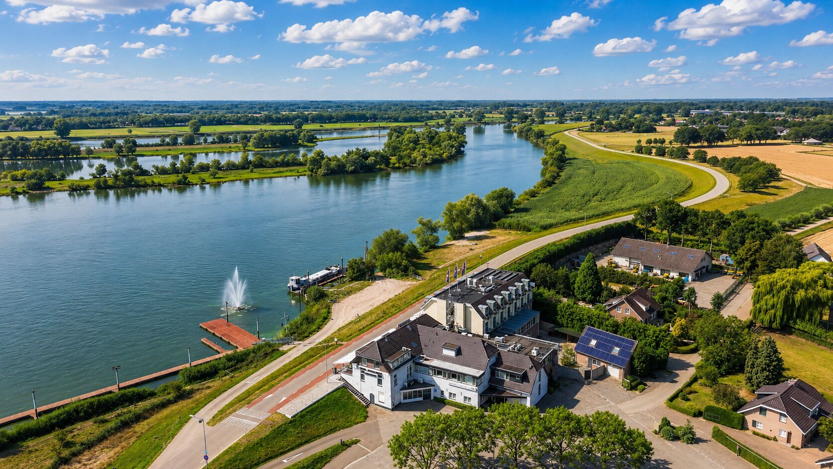 Ejendom ved en flod med en hovedbygning, parkeringsplads og anlagt have.