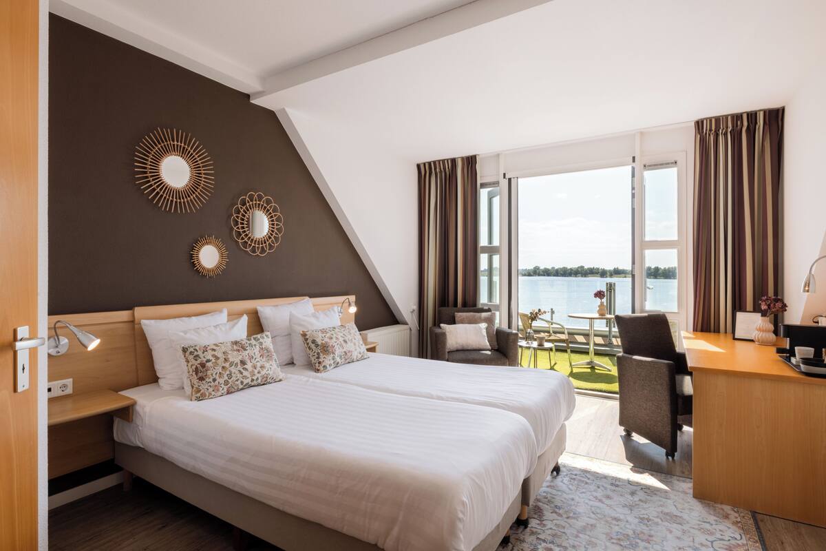 Une chambre d’hôtel avec un grand lit, un bureau et une vue sur l’eau.