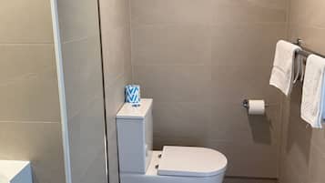 Ein kleines, modernes Badezimmer mit Toilette, Toilettenpapierhalter und Handtuchhalter.