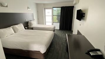 A hotel room with two beds, a desk, a telephone, and a television on the wall.