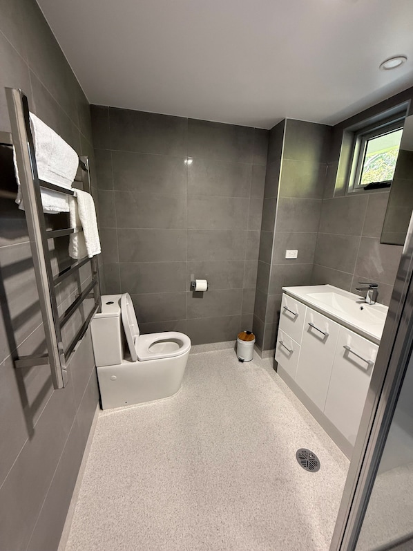 A compact bathroom with a toilet, sink, and a small trash bin. - Brighton Hotel Motel (Brighton)