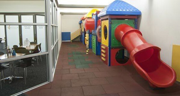 Zona de juegos infantiles con un tobogán rojo y diversas estructuras recreativas.