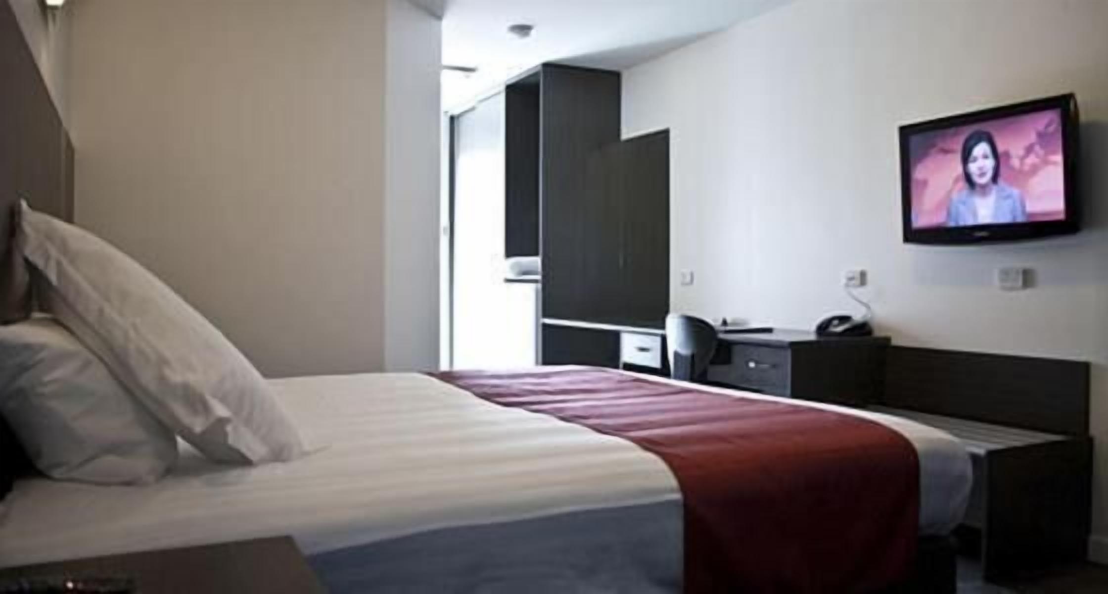 Ett hotellrum med en säng, ett skrivbord, en stol, en tv och en garderob.