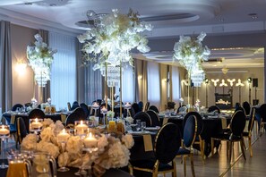 A banquet hall with round tables, chandeliers, and floral centerpieces. - Royal Park Hotel And Spa (Mielno)