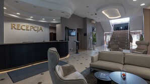 Zona de recepción con mostrador, asientos y una escalera que lleva a un nivel superior.