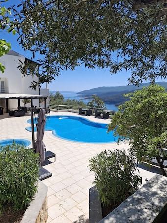 Una piscina al aire libre, sombrillas, sillones reclinables de piscina