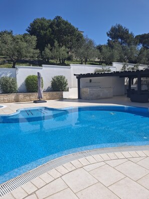 Una piscina al aire libre, sombrillas, sillones reclinables de piscina