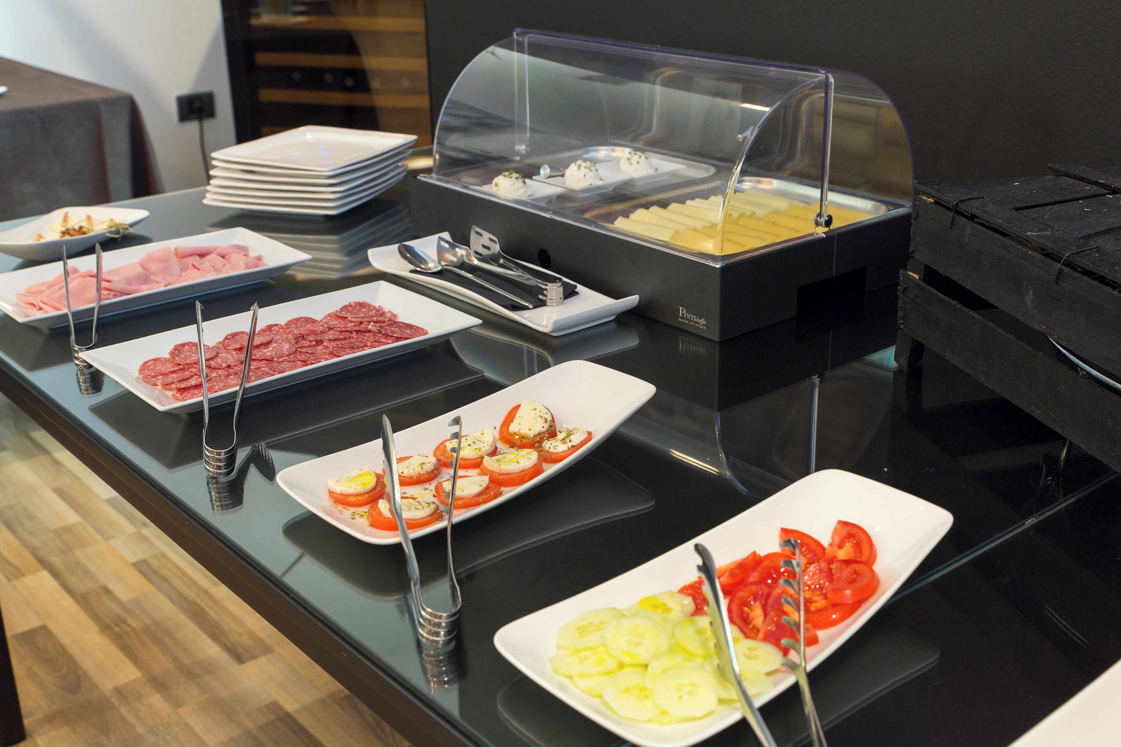 A buffet with various food options including sliced meats, cheeses, and vegetables.