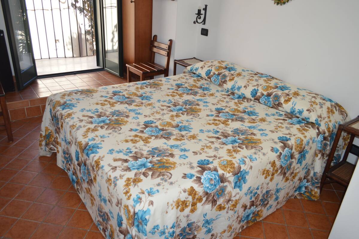 A bedroom with a large bed, a chair, and a small table.