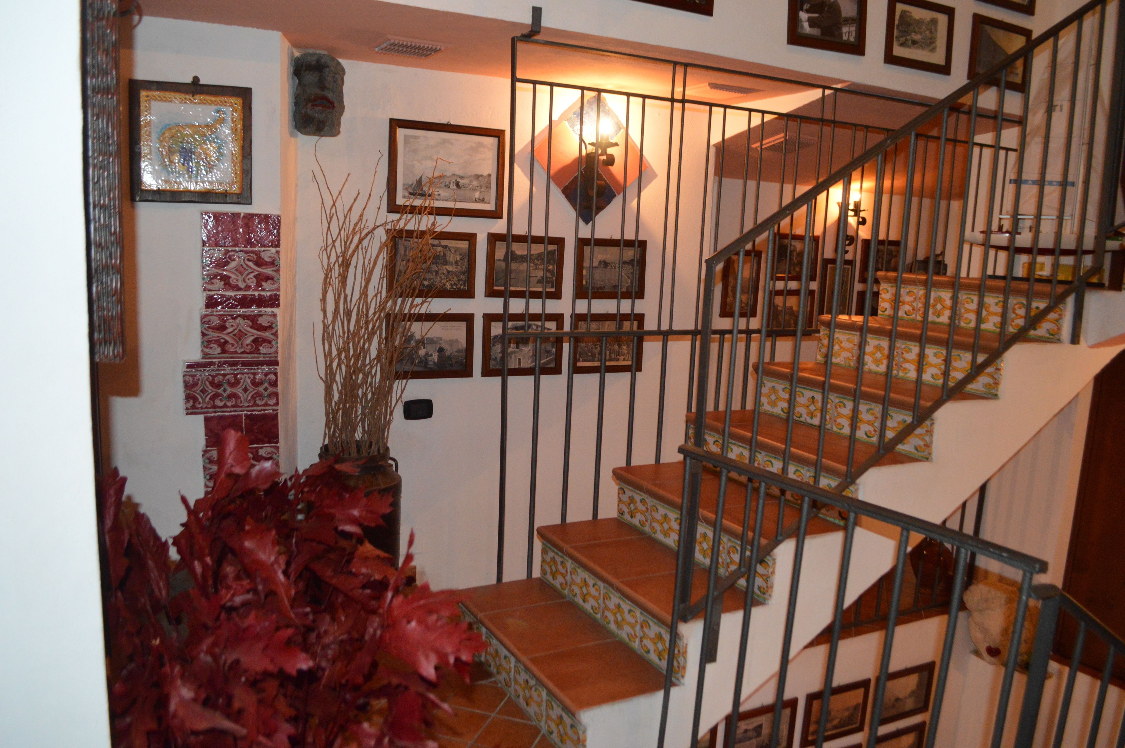 A staircase with a metal railing, surrounded by framed pictures and a decorative wall.