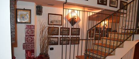 A staircase with a metal railing, surrounded by framed pictures and a decorative wall.