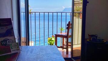 Un balcón con vista al mar, una silla, una mesa y un letrero que indica Wi-Fi gratuito.