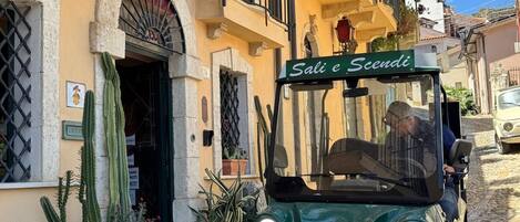Un vehículo verde estacionado frente a un edificio con un letrero que dice 'Sal e Scendi'.