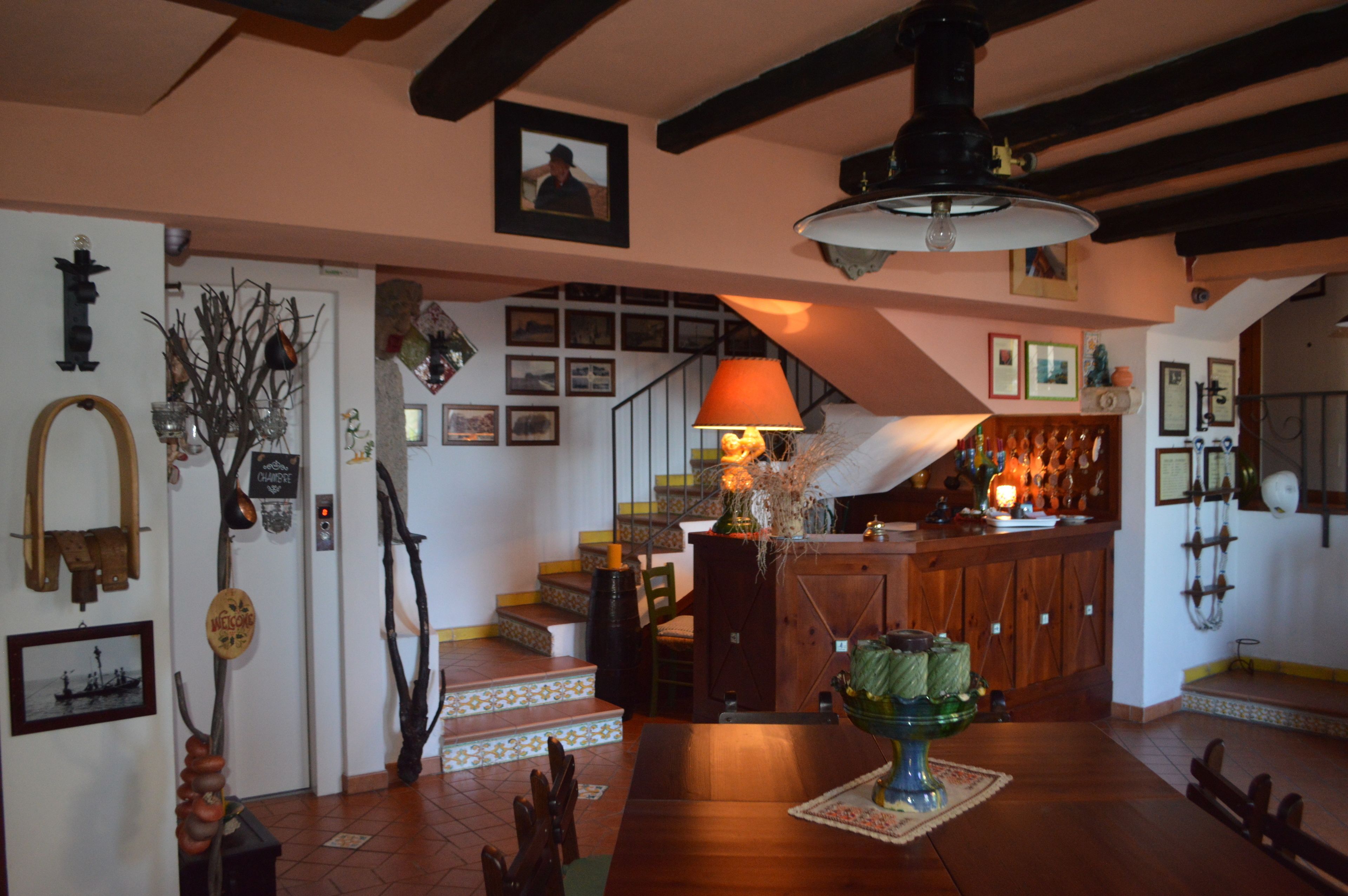 A cozy interior with a wooden dining table, a staircase, and various wall decorations.