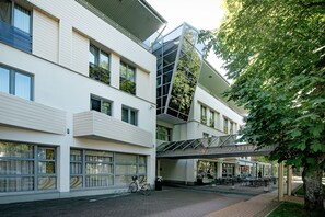 A hotel with a modern architectural design, featuring a prominent glass facade and a covered outdoor seating area. - Palangos Vetra (Palanga)