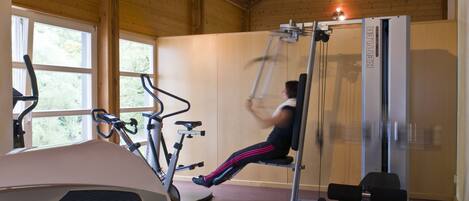A gym with exercise equipment including a stationary bike, a treadmill, and a cable machine.